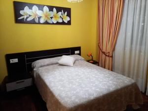een slaapkamer met een bed en een bloemschilderij aan de muur bij Vacaciones in Cedeira