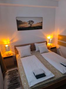 a bedroom with two beds with lamps and a tree on the wall at Penzion Angelika in Bratislava