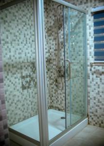 y baño con ducha y puerta de cristal. en Estben guesthouse, en Kwabenyan