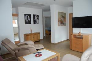 uma sala de estar com uma televisão, cadeiras e uma mesa em Warendorf 12 em Warendorf