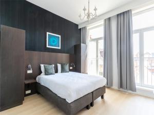 a bedroom with a large bed and a large window at Lace Hotel in Bruges