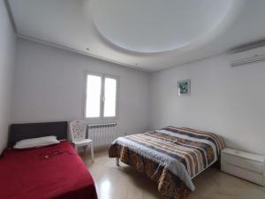 a white bedroom with a bed and a window at Villa Kenais Sunset in Taguermess