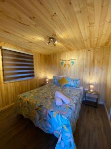 - une chambre avec un lit dans une pièce en bois dans l'établissement Cabañas Quina Nativa, à Quinamávida