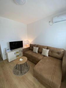 ein Wohnzimmer mit einem braunen Sofa und einem Tisch in der Unterkunft Апартман Милица in Banja Koviljača + 9 Fotos