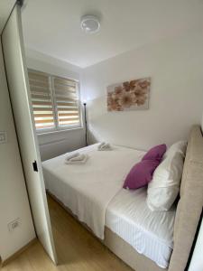 ein Schlafzimmer mit einem Bett mit lila und weißen Kissen in der Unterkunft Апартман Милица in Banja Koviljača