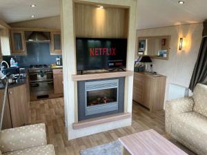 a living room with a tv and a fireplace at Natland Caravan Park in Kendal