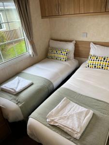 two beds in a small room with a window at Natland Caravan Park in Kendal