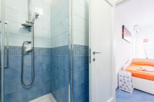 y baño con ducha de azulejos azules. en Appartamento Relais sul mare 6 ospiti, en Meta