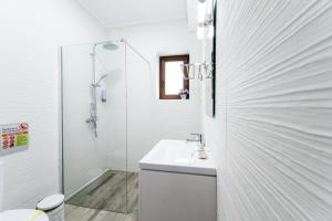 a white bathroom with a sink and a shower at Cross Caraiman View 2 in Buşteni