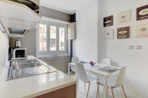 een witte keuken met een witte tafel en stoelen bij La Casa Sui Musei Vaticani in Rome