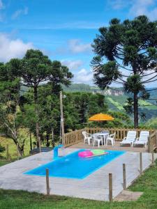 uma piscina com uma mesa e cadeiras e um guarda-sol em Casa aconchegante em meio a natureza em Caxias do Sul