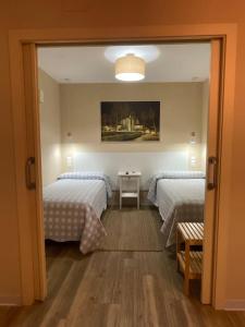 1 Schlafzimmer mit 2 Betten und einem Spiegel in der Unterkunft La Puerta del Valle in Villafranca del Bierzo