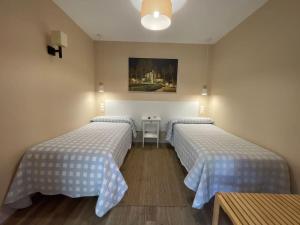 una camera con due letti e un tavolo e un quadro di La Puerta del Valle a Villafranca del Bierzo