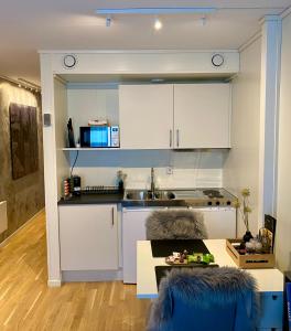 a kitchen with white cabinets and a table at Experience a Cozy Getaway Near Pulpit Rock in Strand