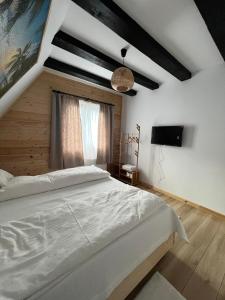 a bedroom with a white bed and a window at CabanA Oscar in Borşa