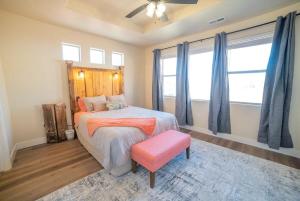 a bedroom with a bed with a pink stool and windows at 3x3 Sanctuary at Kanab - New West Properties in Kanab