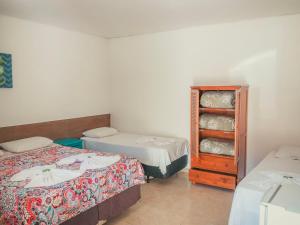 a room with two beds and a dresser in it at Pousada Acqua Infinity in Bertioga