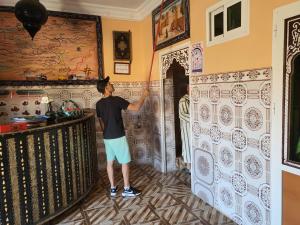 a man painting a wall in a room at Dar Ilyana in Tamezmoute