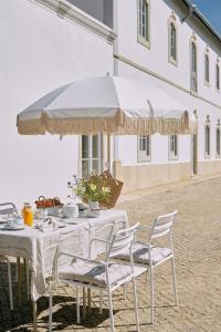 a white table with chairs and an umbrella at Solar do Bisavô in Bordeira