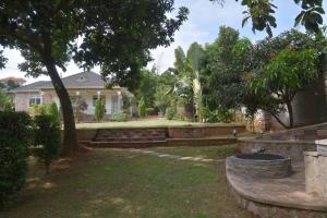 a yard with a house with a tree and benches at Lisa's 4 bedroom villa in Kampala