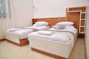 2 camas en una habitación con sábanas blancas en Lisa's 4 bedroom villa, en Kampala