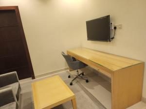 Zimmer mit einem Schreibtisch und einem TV an der Wand in der Unterkunft شقق سكاي الفندقية in Arar