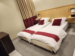 a hotel room with two beds with red pillows at شقق سكاي عرعر الفندقية in Arar