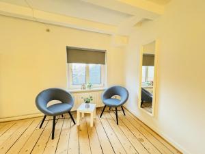 aday - Randers Beautiful Central 2 bedrooms Apartment في راندرس: كرسيين زرقين وطاولة في الغرفة