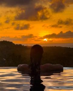 a woman sitting in the water at sunset at Uluwatu Sunset Hills in Uluwatu