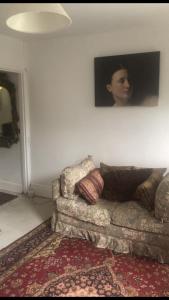 a couch in a living room with a picture on the wall at Komorebi Healing House in Dawlish