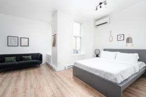 a white bedroom with a bed and a couch at Boutique Lofts Notre Dame in Montreal