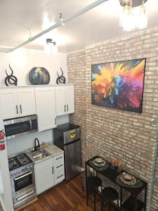 una cocina con armarios blancos y una pintura en la pared en The Harlem Getaway, en Nueva York