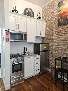 uma cozinha com armários brancos e electrodomésticos de aço inoxidável em The Harlem Getaway em Nova York
