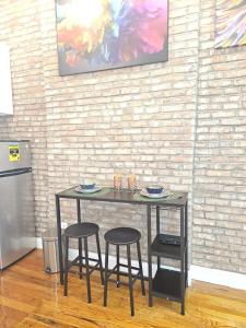 a table and two stools in a room with a brick wall at The Harlem Getaway in New York
