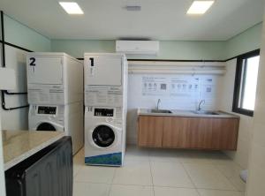 een wasruimte met een wasmachine en droger en een wastafel bij Conforto próximo ao Farol in Salvador