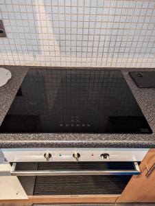 a stove top in a kitchen with black tiles at The Pinnacle 4/5 in Glasgow