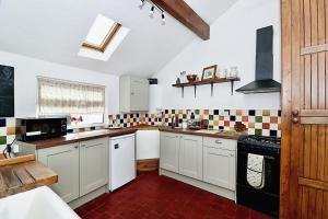 a large kitchen with white cabinets and black appliances at Milk & Honey Cottage 2 Bed Ironbridge Retreat in Broseley