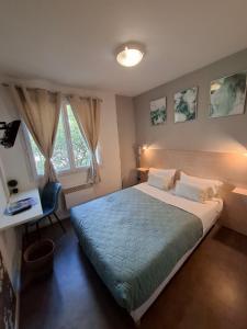 Schlafzimmer mit einem großen Bett, einem Schreibtisch und einem Fenster in der Unterkunft Hotel Au Bon Sejour in Vitry-le-François