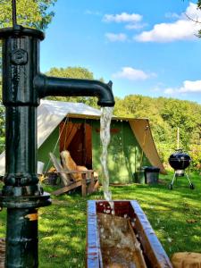 una fuente de agua en un campo con una tienda de campaña en Kampeerbeleving Dijksehoeve, en Nistelrode