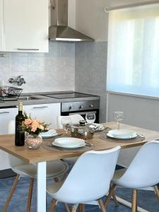 a kitchen with a wooden table and white chairs at Apartments Ema in Sali