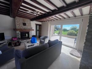 ein Wohnzimmer mit einem blauen Sofa und einem Kamin in der Unterkunft Villa CHESTER 9 km d'Omaha Beach in Trévières