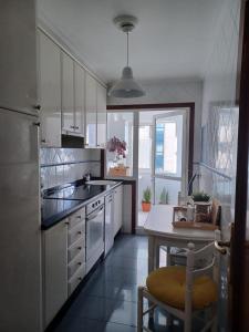 une cuisine avec des placards blancs, une table et une salle à manger dans l'établissement Piso con piscina próximo a Plaza de España, à Vigo
