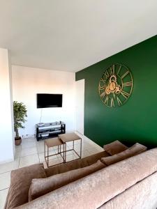 a living room with a large clock on a green wall at The Sunrise, Spacious, fully equipped, 2 parkings, 8p, tramway 1,2,4 in Montpellier
