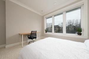 a white bedroom with a desk and a bed and a window at Luxurious 6-Bedroom Mansion Near UBC in Vancouver