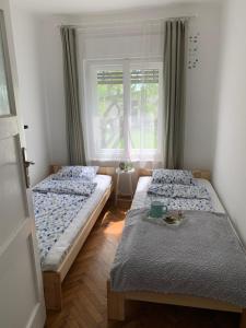 two beds in a room with a window at Füge Vendégház Csopak in Csopak