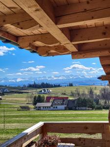 a view of a farm from a porch with a wooden roof at Domki Na Grapie - z widokiem na Tatry in PyzÃ³wka