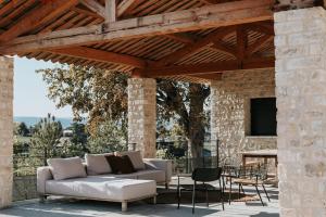 un patio con sofá y sillas bajo una pérgola de madera en Garenne en Livron-sur-Drôme