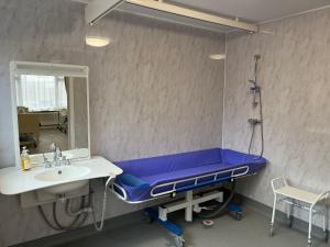 a hospital room with a blue bed and a mirror at The Rose Marie Lodge in Clacton-on-Sea