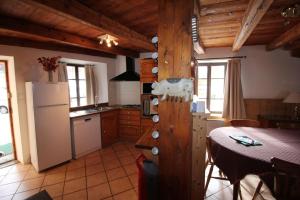 a kitchen with a table and a white refrigerator at Atmospheric, original stone chalet in Meribel in Les Allues +28 photos