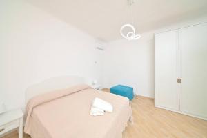 biała sypialnia z łóżkiem i niebieską walizką w obiekcie Villa Aida w mieście Ischia